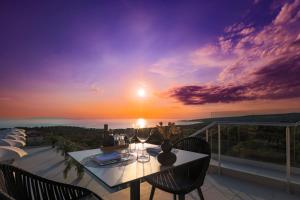 a table and chairs on a balcony with a sunset at Hotel In Excelsis in Novalja