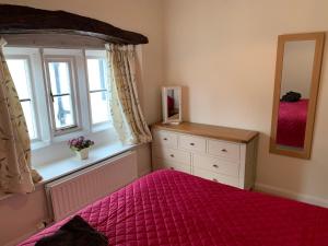 a bedroom with a bed and a dresser and a window at Eagle Cottage in Penrith