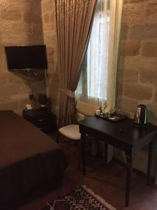 a bedroom with a bed and a desk and a window at Sazeli Boutique Hotel in Baku