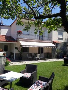 a yard with chairs and tables and a building at Elena Rooms-Apartments in Asprovalta