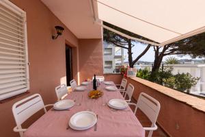 einen Tisch mit weißen Stühlen und eine rosa Tischdecke auf dem Balkon in der Unterkunft Bravissimo Vil·les Brusi C S'Agaró in S'Agaró