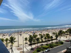 ein Strand mit vielen Sonnenschirmen und dem Meer in der Unterkunft Pe na Areia Canto do Forte, Wi-Fi,Estacionamento in Praia Grande