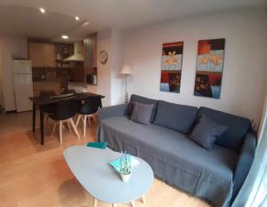 a living room with a blue couch and a table at Precioso apartamento en El Tarter frente a pistas in El Tarter