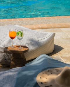 two wine glasses sitting on a table next to a swimming pool at Petrino Eco Village in Afitos