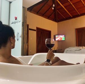 a woman sitting in a bath tub holding a glass of wine at Adega Cipó Pousada Serra do Cipó in Serra do Cipo