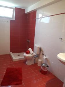 a red and white bathroom with a toilet and a sink at Elena Rooms-Apartments in Asprovalta