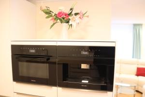 a black oven in a living room with a vase of flowers at Liebevoll renoviertes Haus mit großem Garten in Dresden in Dresden