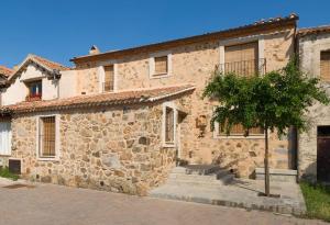 a stone building with a tree in front of it at El Zaguán de Cabanillas in Cabanillas del Monte