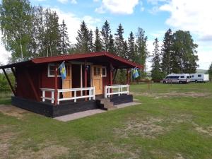a small red house with a porch in a field at Camping Djupdalen in Ekshärad