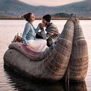 two people sitting on top of a large boat in the water at Uros Caminos del Titicaca Peru in Puno