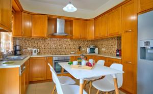 una cocina con armarios de madera y una mesa y sillas blancas. en Villa Spiros Imerolia Kassiopi en Kassiopi