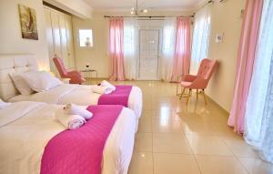 two beds in a room with pink and white at Villa Spiros Imerolia Kassiopi in Kassiopi