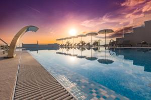 a pool on the roof of a building with a sunset at Hotel In Excelsis in Novalja