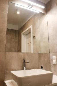 La salle de bains est pourvue d'un lavabo et d'un miroir. dans l'établissement Lemon Park Apartments Parking Gratis, à Poznań