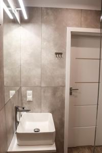 uma casa de banho com um lavatório branco e um espelho. em Lemon Park Apartments Parking Gratis em Poznań