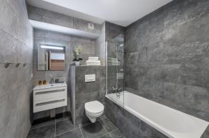 y baño con aseo, bañera y lavamanos. en Perle de Savoie - Apt A103 - BO Immobilier, en Châtel