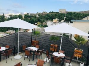 a patio with tables and white umbrellas on a roof at Kore Guest House in Gjirokastër
