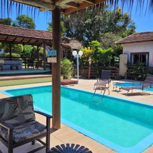 a swimming pool with a chair and a table at Pousada Mares do Santinho in Florianópolis