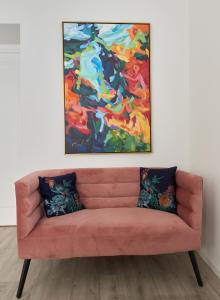 a pink couch in a room with a painting on the wall at New apartment next to Cathedral Square in Vilnius