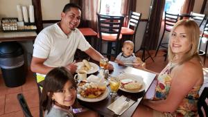 una familia sentada en una mesa comiendo comida en un restaurante en Combate Beach Resort, en Cabo Rojo