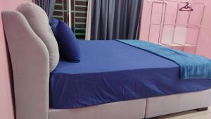 a bed with a blue blanket on top of it at PRESTIJ H0MESTAY in Balik Pulau