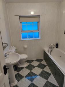 a bathroom with a toilet and a tub and a sink at 6 Connorville in Luddan