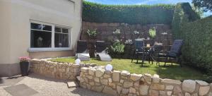 a backyard with a stone wall and a table and chairs at Ferienwohnung MIA in Flußbach
