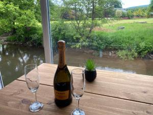 una botella de vino sentada en una mesa con dos copas en Riverbank Cottage Lake District Double Balcony en Egremont