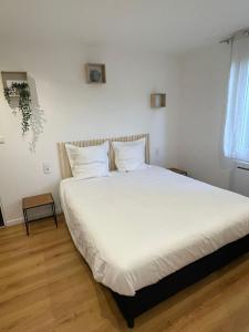 una camera da letto con un grande letto con lenzuola e cuscini bianchi di Le Sommelier Centre Ville a Épernay
