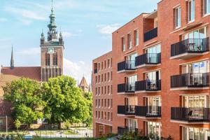 a brick building with a clock tower in the background at Charming Old Town Gdańsk by Renters in Gdańsk