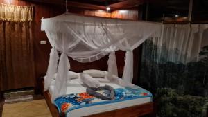 uma cama de dossel com uma pessoa deitada sobre ela em Bukit Lawang Hill Resort em Bukit Lawang