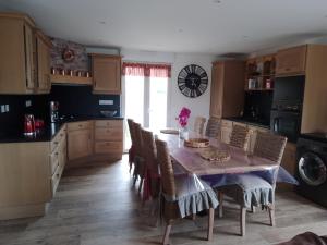 a kitchen with a table with chairs and a clock on the wall at Résidence Les beaux jours in Neufchâtel-Hardelot