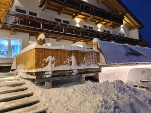 a building with a bench in the snow at Alpen Gasthof Apartments Hohe Burg in Trins