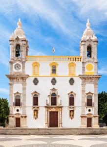 un grand bâtiment blanc avec une tour d'horloge dans l'établissement Arty Casa, à Faro 17 autres photos