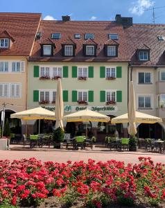 um edifício com guarda-sóis, mesas, cadeiras e flores em Hotel Gasthof Jägerstüble em Freudenstadt