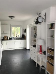 een keuken met witte kasten en een klok aan de muur bij Haus Margarete Dornum mit Wallbox in Dornum