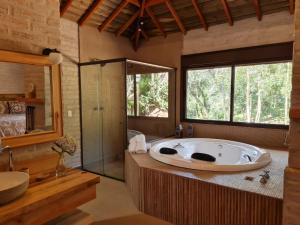 a large bathroom with a tub and a shower at Pousada Toca Da Coruja in Monte Verde