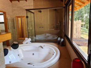 a large white tub in a bathroom with a bath tub at Pousada Toca Da Coruja in Monte Verde +254 photos