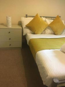 2 camas con almohadas amarillas y mesita de noche en Global Boutique Relocation Ltd 2Bed -free parking en Hatfield