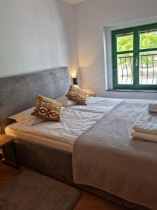 sypialnia z łóżkiem z poduszkami i oknem w obiekcie TU i TERAZ apartament w Ustce