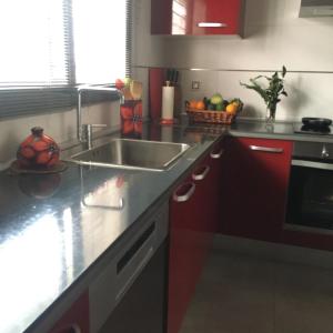 una cocina con armarios rojos y fregadero en Alquiler casa veraneo Málaga Valleniza, en Málaga