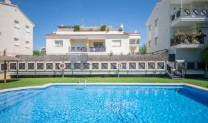 a swimming pool in front of two buildings at R129 Apartamento con terraza y piscina comunitaria cerca de la playa in Calafell