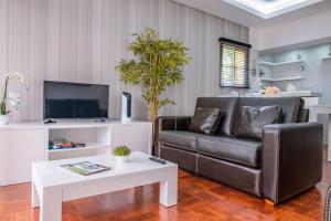 ein Wohnzimmer mit einem Ledersofa und einem TV in der Unterkunft Canico Sea Garden by Madeira Sun Travel in Caniço