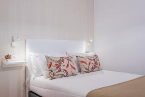 ein weißes Schlafzimmer mit einem Bett mit zwei Kissen in der Unterkunft Canico Sea Garden by Madeira Sun Travel in Caniço
