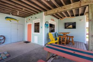 a porch with a bench and a table at One-of-a-Kind Beach Home with Lounge Bar Game Room in Galveston