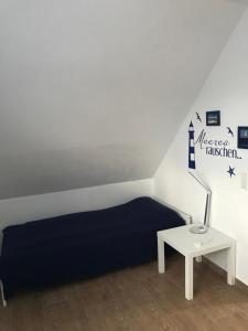 a bedroom with a bed and a table with a lamp at Feriendomizil Dornum Haus Margarete mit Wallbox in Dornum