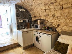 eine Küche mit einer Spüle und einer Waschmaschine in der Unterkunft Tao Stones - Alloggio in pietra in Conversano