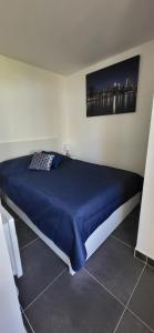 uma cama num quarto com um cobertor azul em Une Escale en bord de Plage avec piscine et jardins em Le Grau-du-Roi
