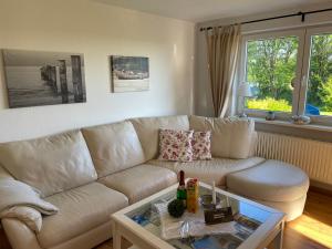 a living room with a white couch and a glass table at Nordseeblick Ferienhaus in Wobbenbüll