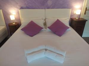 1 cama blanca grande con 2 almohadas moradas en B&B Villa la Bouganville en Camaiore